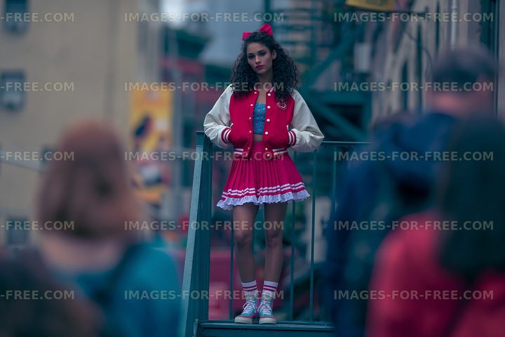 Girl in red outfit stands on steps in busy urban setting