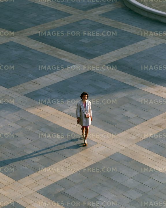Person walking on a patterned stone pavement in outdoor setting