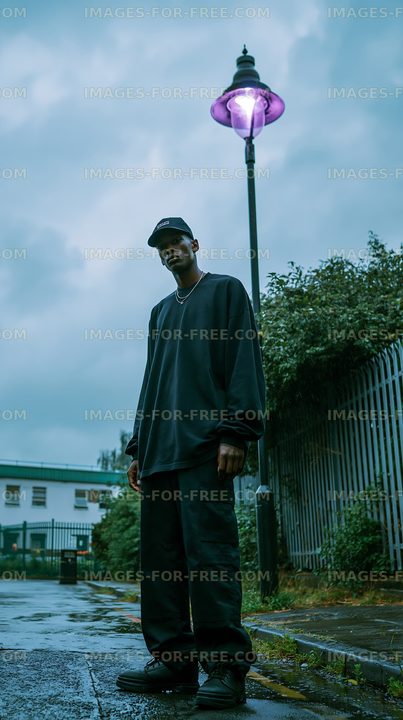 Man stands under street lamp in urban area on cloudy day