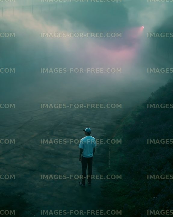 Person standing on foggy road at dusk
