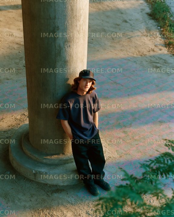 Young man leaning against a stone pillar on a sunny day