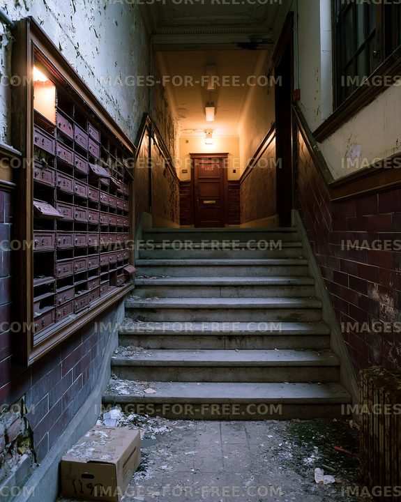 Stairs leading to a dimly lit hallway with old mailboxes