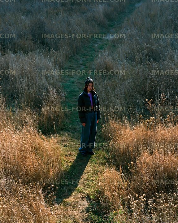 Person standing in a grassy area with tall plants around