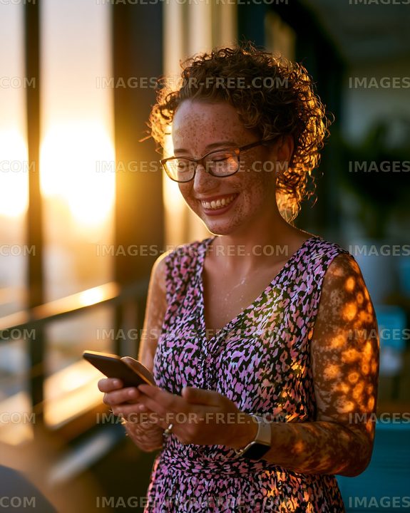 Woman smiling while using smartphone during sunset