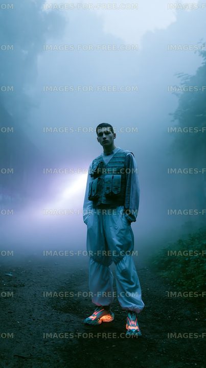 Man standing on a foggy road wearing a vest and pants