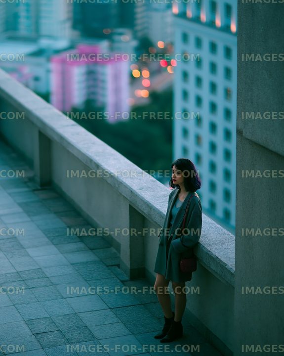 Woman standing alone on city rooftop during dusk