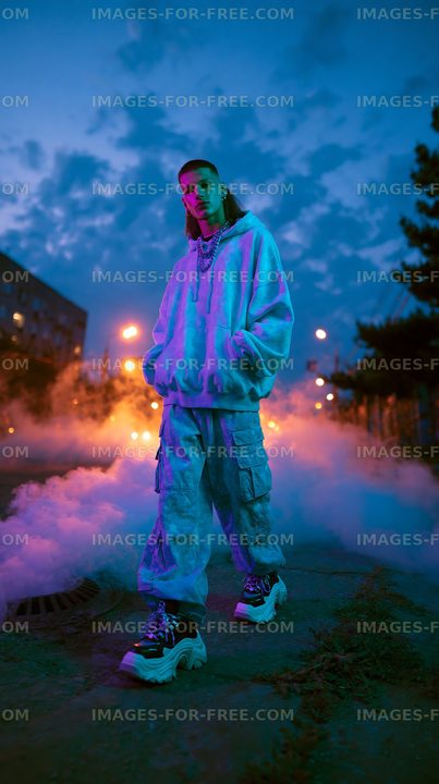 Person standing on street surrounded by fog at dusk