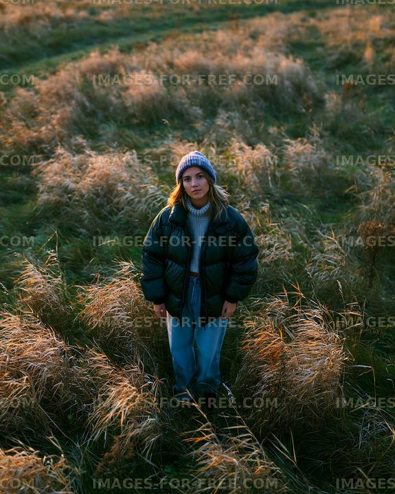Woman standing in a field of grass during sunset