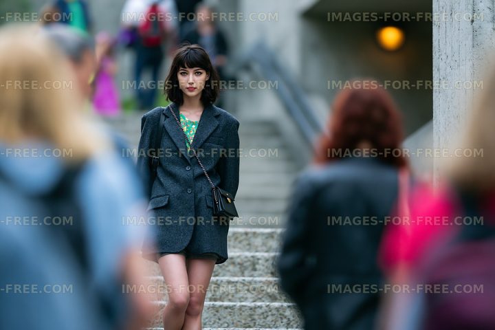 Young woman stands on stairs in urban setting surrounded by people