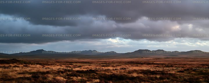 Panoramic grassland and mountains under storm clouds