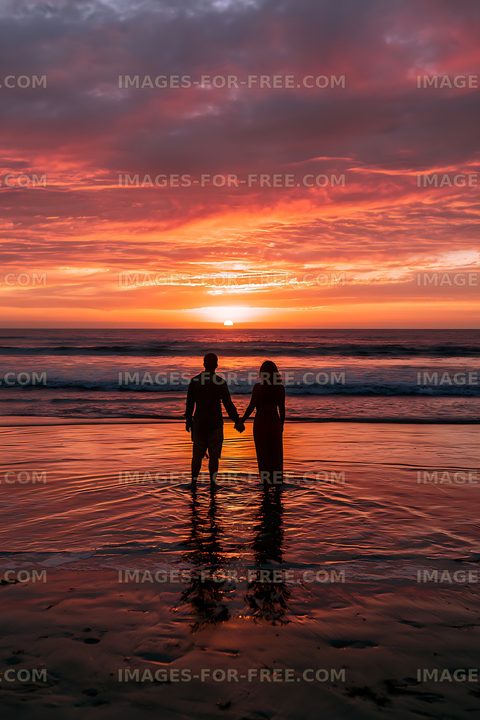 Silhouetted couple standing in shallow water at sunset