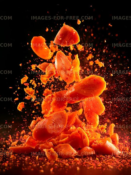Orange fruit exploding into pieces against a dark background
