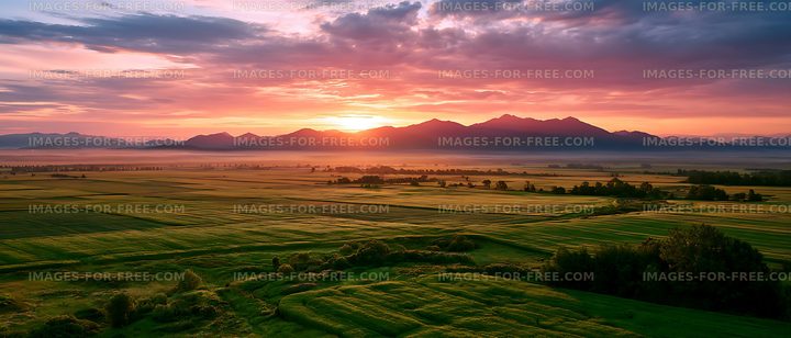 Colorful sunset above farmland and distant mountains